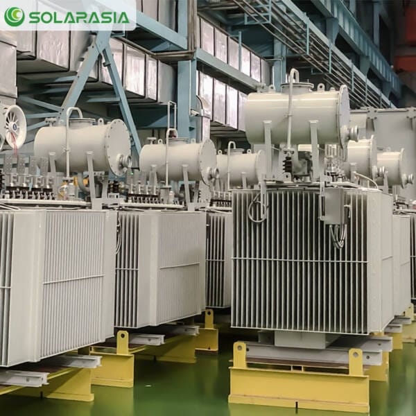 Technician performing final tests or inspection on a large 50kV oil-immersed transformer in the factory.